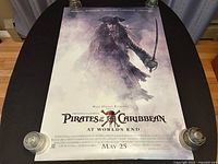 Photo showing full front side of the Pirates of the Caribbean: At World's End movie poster featuring Captain Jack Sparrow emerging from fog with sword, movie title and release date May 25