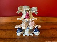 Full view of the six Royal Doulton miniature Pretty Ladies figurines arranged on the original tiered ceramic display stand against a red background.
