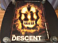Top view of the double-sided poster laid flat on a table, showing the main skull image artwork and text.