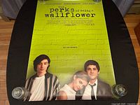 Full view of the poster laid flat on a table, visible full image of the three main actors and poster text.