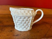 Side view showing basketweave texture and spout of white china creamer.