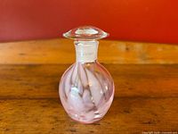 Front view of delicate clear blown glass perfume bottle with pink swirl accents and original stopper in place on neck, showing Made in Japan label on neck.