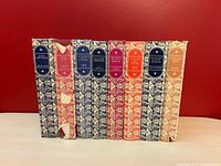 Front view of the spines of 8 hardcover books from The Companion Book Club with colorful patterned cloth bindings and oval title labels.