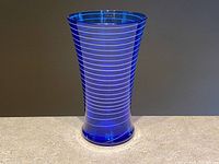 Front view of cobalt blue glass vase with white spiral stripe wrapping around from base to rim.