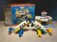 Photo showing the two jet planes, airport terminal, and the original box in the background with visible heavy wear