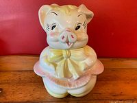 Front view of the pig cookie jar showing detailed facial features, yellow bow, and pink skirt.