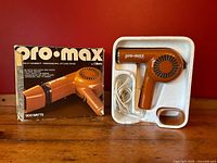 Vintage brown/orange Gillette Pro Max hair dryer with extra wide nozzle and original styrofoam packaging, placed next to original branded box.