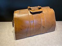 Front view of vintage Queen Leather doctor's bag showing caramel brown cowhide leather with natural scratches and patina.