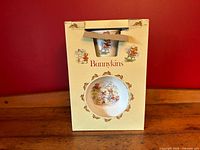 Original box for the Royal Doulton Bunnykins 3-piece children's dish set showing front selective cutaway revealing bowl and mug inside.