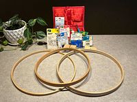 Overview of the sewing basket, vintage notion packages, and three wooden embroidery hoops laid out on a flat surface