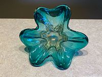 Top view of the vintage art glass bowl shaped like a shamrock showing teal and amber tones and star-like center.