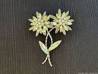 Front view of the Sherman brooch showing two crystal flowers with navette and round rhinestones in a silver-tone twisted stem design on a dark fabric background.