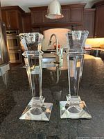 Pair of clear geometric Czech crystal candlesticks on a black countertop with kitchen background.