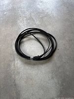Coiled black soaker hose on concrete floor showing general length and shape.