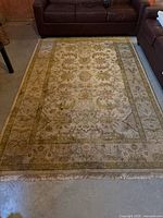 Full view of the IKEA Kashan area rug placed on concrete floor between two brown leather sofas, showing front surface design and colors.