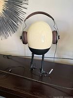 Vintage Sennheiser Momentum on-ear headphones displayed on a stand showing brown Alcantara ear pads and headband with attached audio cable.