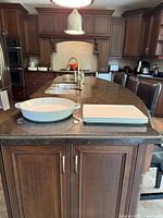 Wide view of the large round white ceramic serving dish and three rectangular porcelain dishes on kitchen counter