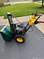 Side profile showing green steel housing, yellow control module, traction tires, and red handle grips