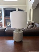 Single grey ceramic table lamp with white shade on a wooden surface