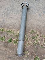 Full length view of a 6 inch diameter metal chimney pipe with a rain/spark cap on top, showing some wear and weathering.