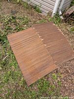 Two wooden vintage adjustable seat covers laid outdoors on grass and dirt showing condition and design.