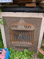 Front image of antique cast iron electric fireplace insert with decorative embossing and rust patina outdoors.