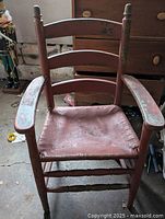 Front view of antique ladder back shaker style chair with red worn paint and woven seat