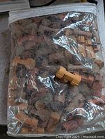 Transparent zippered plastic bag filled with numerous wooden Lincoln Logs pieces, showing variety of semi-cylindrical logs and connector blocks inside.