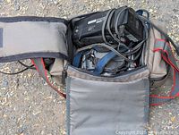 Top view of open gray carrying case showing video camcorder, cables and accessories inside.