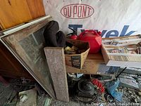 Lot showing red plastic jerry can, window frame, cardboard box with miscellaneous items, coil of black tubing, box of assorted cards, and compressor unit on floor