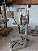 Side angle showing metal drill press stand with lever and drill clamp