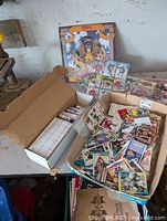 Wide view of two open boxes with numerous loose hockey cards and comic books scattered inside.