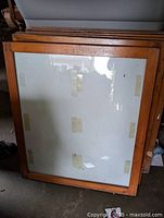 Four solid maple wood picture frames with glass fronts stacked together, showing natural wood grain and glass surface.