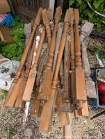 Seven to eleven Victorian wood turned spindles laid in a pile with visible patina, paint residue and wear. Each spindle has a squared block end fitting and carved rounded middle section.