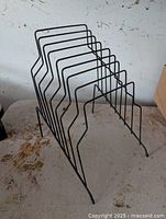 Black metal wire record album display rack stand with dimensions around 10 inches high. The rack has multiple slots to hold vinyl records upright and is in lightly used condition as per seller description.