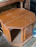Octagonal wood coffee table with paneled sides and visible surface wear.