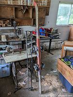 Full view of skis and ski poles leaning against workbench in garage showing size and condition.