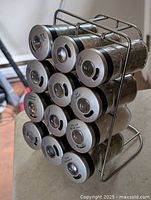 Metal spice jars arranged in the silver metal stand. Visible metal lids with transparent windows.