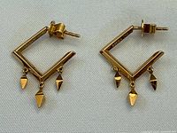 Front view of both earrings showing square hoop shape and three dangling pyramids on each.