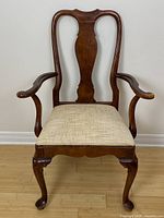 Front view of the mahogany captain's chair showing carved wood frame and beige upholstered seat.