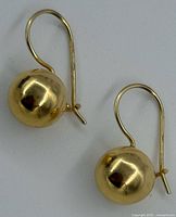 Pair of polished yellow gold ball earrings on white background