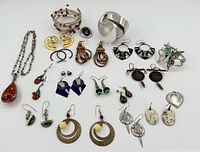 Full lot of handcrafted jewellery including earrings, bracelets, and a pendant necklace arranged on a white background.