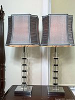 Pair of two modern table lamps with acrylic cube bases and grey fabric ribbed shades on a dark wooden table.