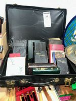 Full lot image showing black suitcase filled with antique and vintage Bibles and religious books in varied colors and sizes.