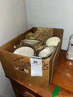 Box containing multiple antique Imperial China tea cups and saucers with 18k gold trim wrapped partially in newspaper.