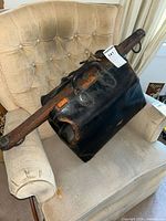 Wooden curved yoke resting inside the leather doctor's bag, showing the shape and metal attachments.