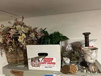 Photo of floral arrangements, metal pelican, white and gray marble vase, and candle holders grouped on a shelf