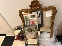 Three mirrors grouped: large gold ornate frame mirror with carved floral details, medium rectangular painted floral frame mirror, small round mirror with wooden base