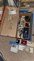 Overview of assorted religious jewelry in cardboard boxes including pearl-like rosary with mother-of-pearl crucifix and various other rosaries and pendants.