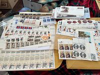 Overhead image showing various sheets and blocks of unused and used stamps, some with historical and international designs.